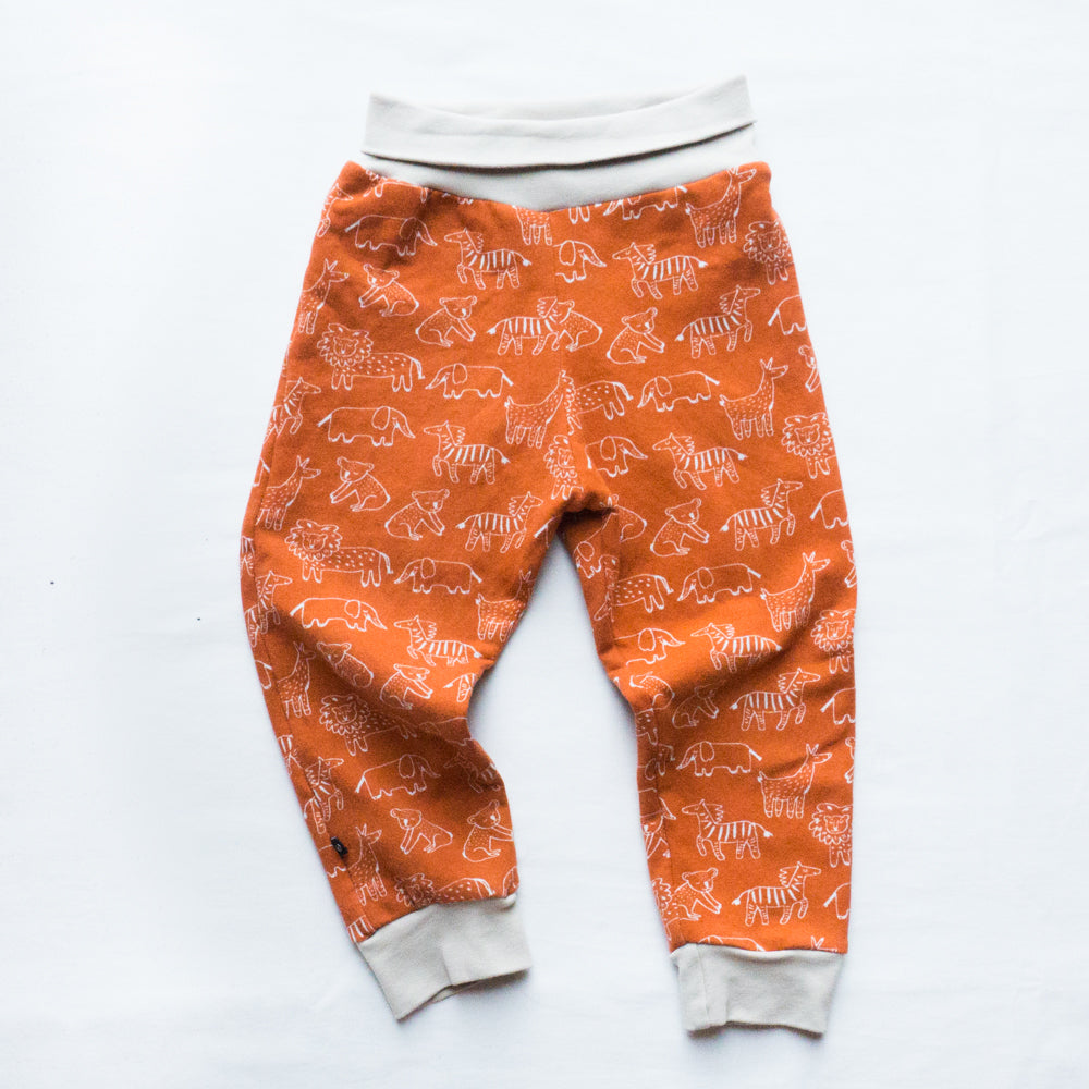 Organic cotton fleece pants with animal print. Primary coliur is organe, with white outlined animals.